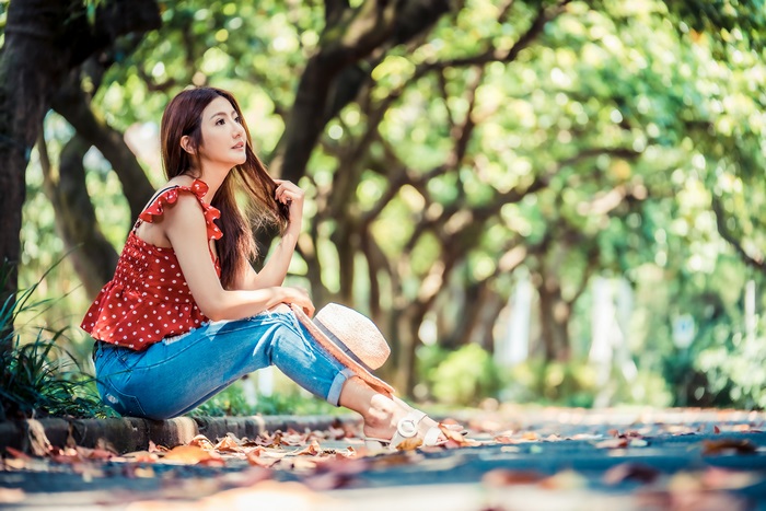 Asian woman with brunette hair sitting in a park