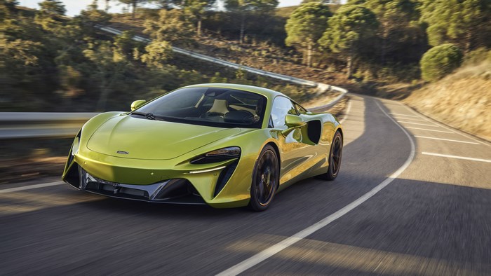 Green McLaren Artura driving on a winding road