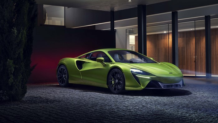 Green McLaren Artura supercar parked outside modern house