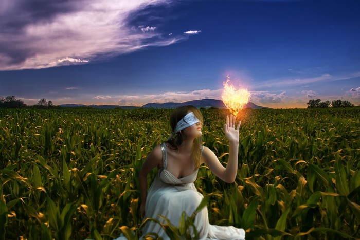 Blindfolded woman in cornfield with fiery heart