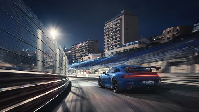 Blue Porsche 911 GT3 (992) driving on a race track at night