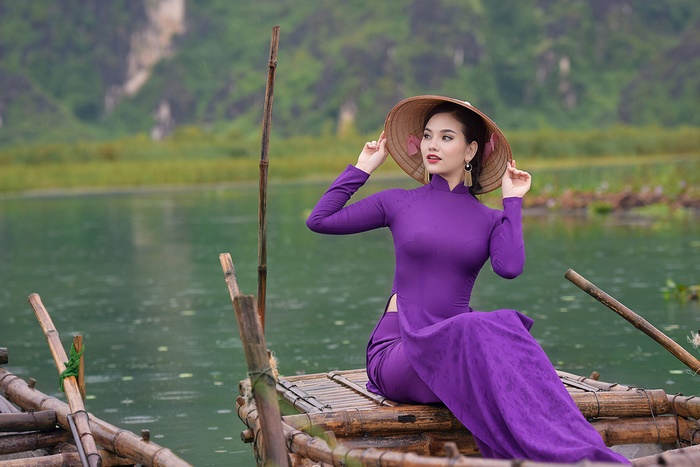 Woman in purple dress and conical hat on a boat