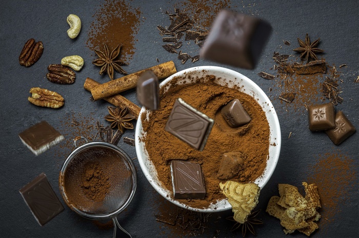 Chocolate, nuts, cinnamon, and star anise on a dark surface