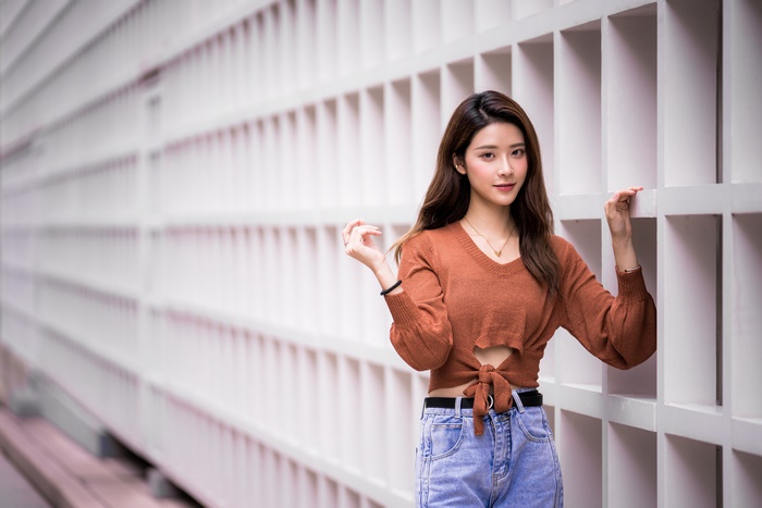 Asian woman with brunette hair in a brown sweater and jeans