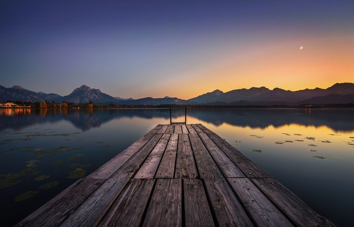 Wooden pier on a lake at sunset with mountains