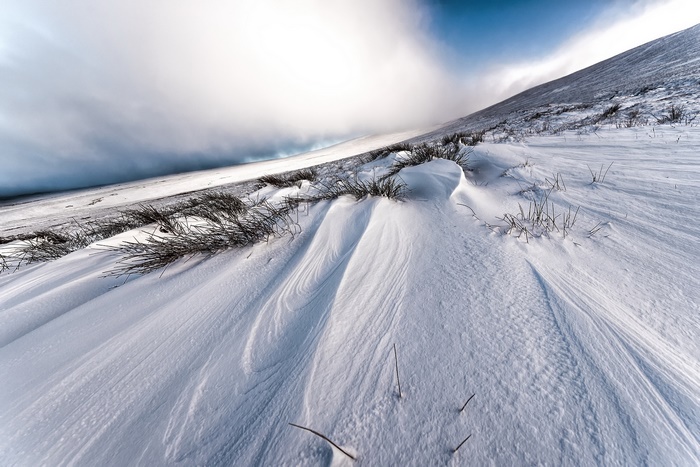 Snowy Hillside with Wind-Swept Snow and Grass