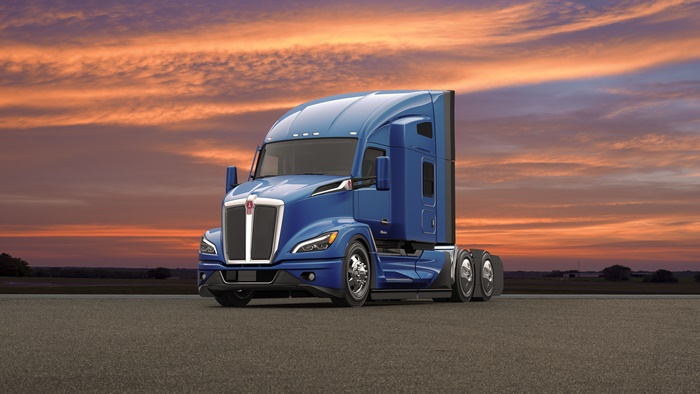 Blue Kenworth T680 semi-truck on a road at sunset