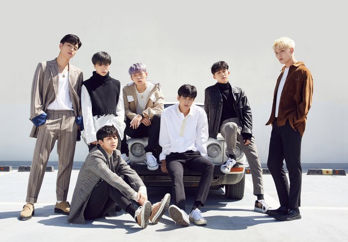 iKON members posing in front of a car