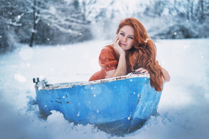 Redhead woman in a blue boat in the snow
