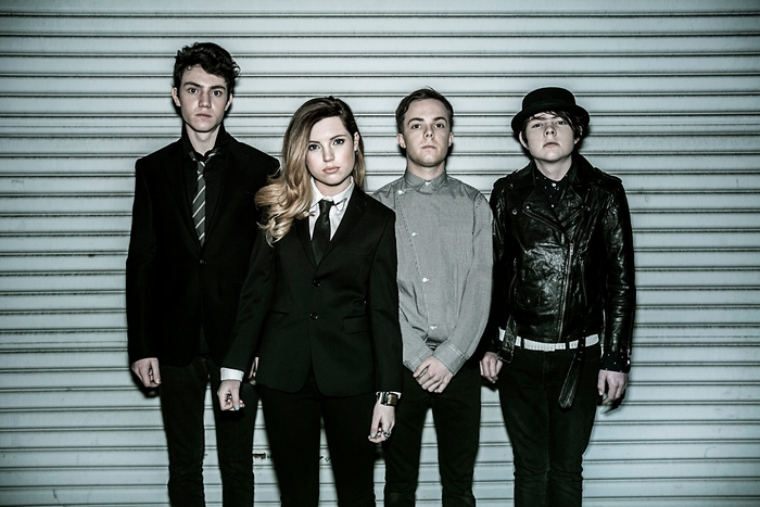 Echosmith band members posing in front of a metal wall