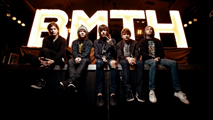 Bring Me The Horizon band members sitting in front of large illuminated letters