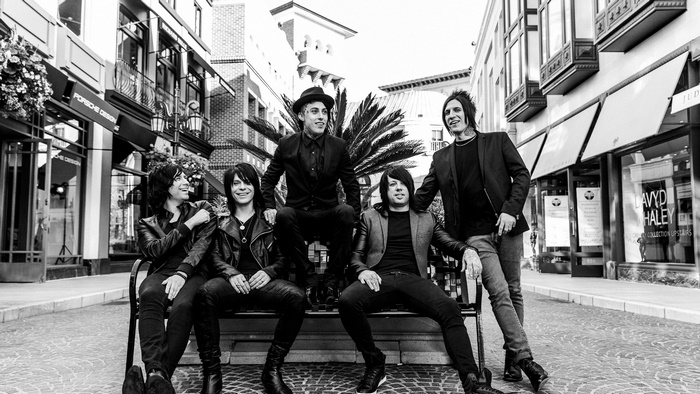 Falling In Reverse band members posing on a bench