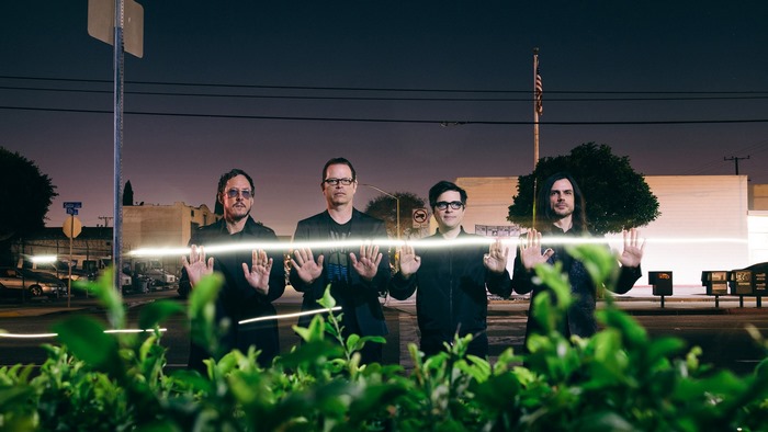 Weezer band members standing in front of a building at night