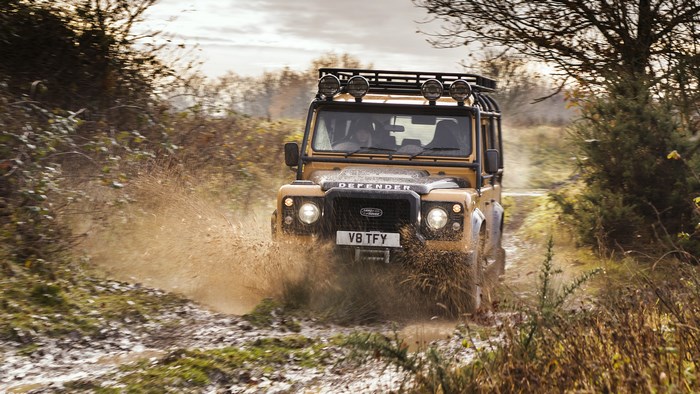 Yellow Land Rover Defender driving through mud