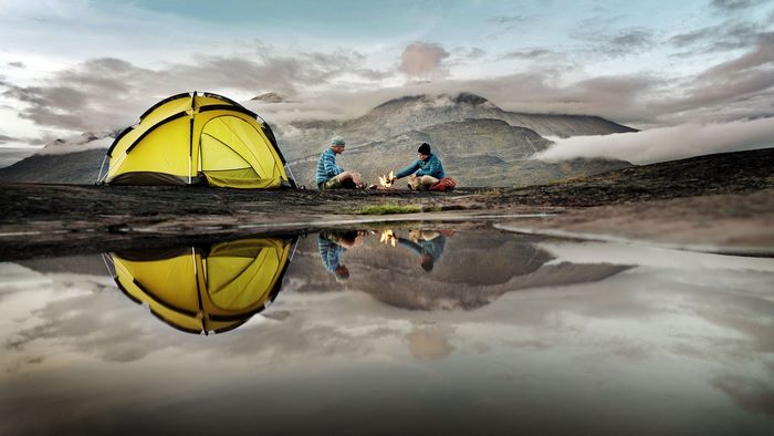 Camping with a tent and campfire by a reflective pool