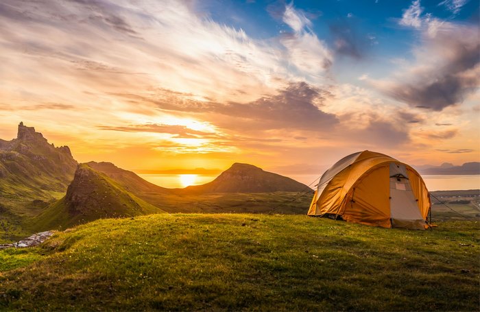 Tent camping on a grassy hill at sunset