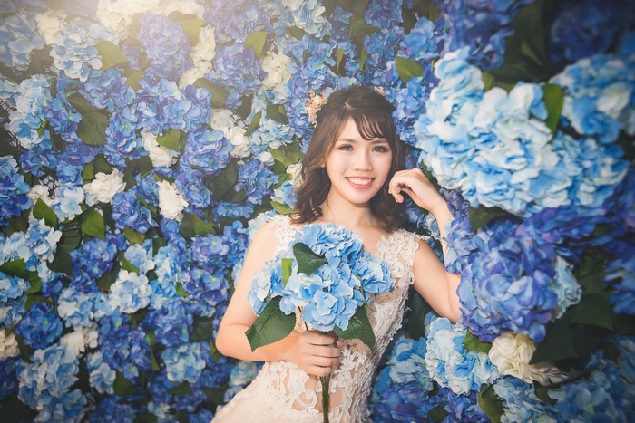 Young Asian woman in a white dress holding blue flowers