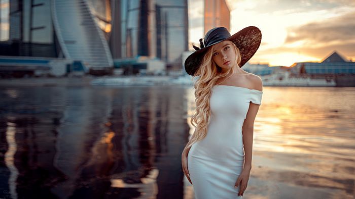 Woman in white dress and hat by the water