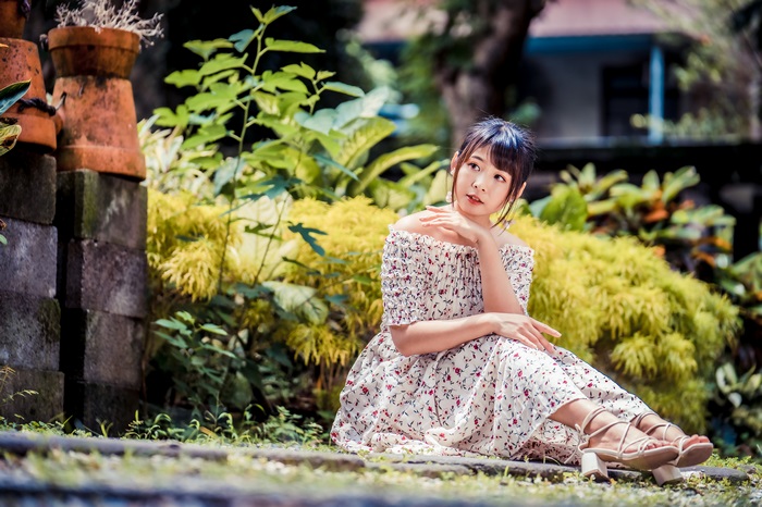 Asian woman in floral dress sitting in garden