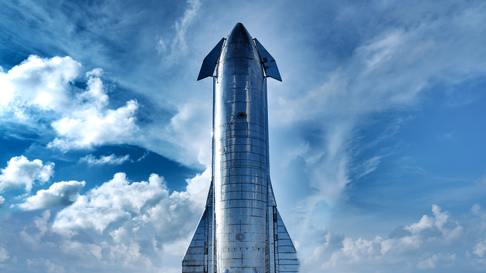 SpaceX Starship rocket against a cloudy blue sky