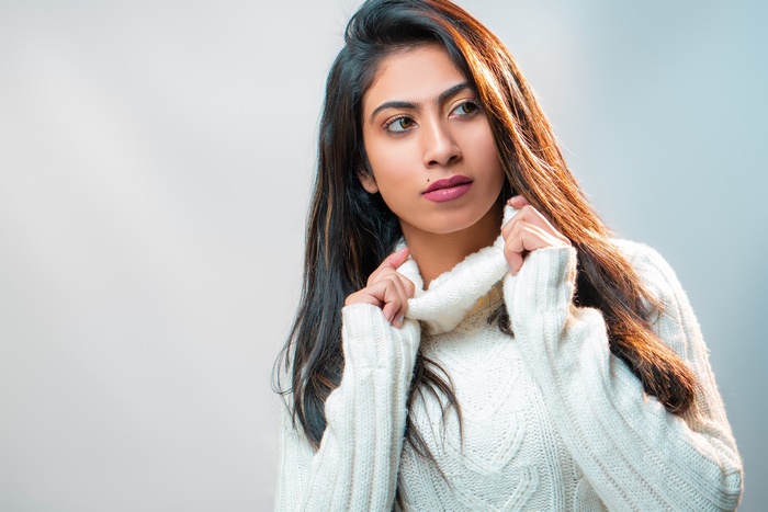 Woman with dark hair wearing a white sweater