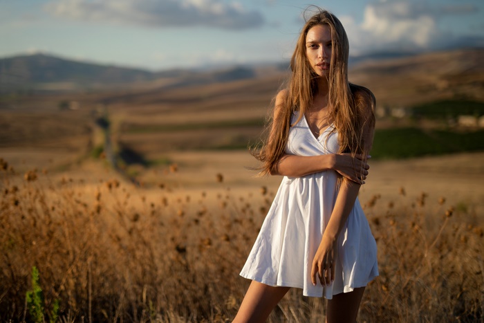Woman with long hair in a white dress in a field
