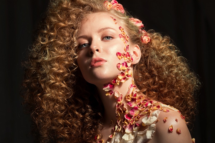 Woman with curly hair and flower petals