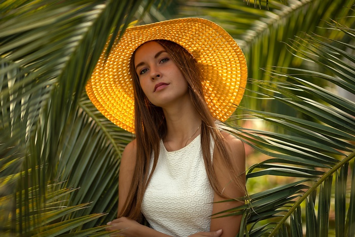 Woman in a yellow hat among palm leaves