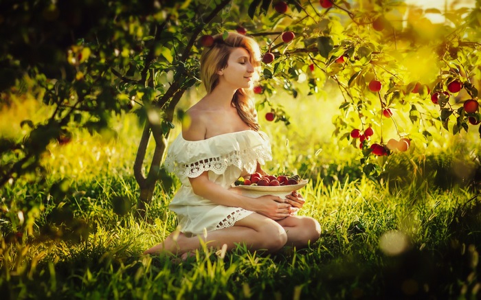 Woman in white dress picking fruit from a tree