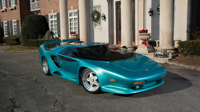 Teal 1993 Vector WX3 sports car parked in front of a mansion