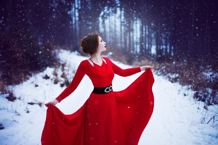 Woman in red dress posing in snowy forest
