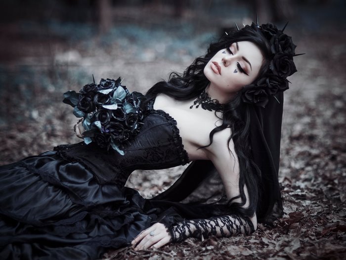 Gothic woman in black dress with black roses