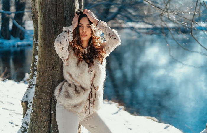 Woman in fur vest by a tree in winter