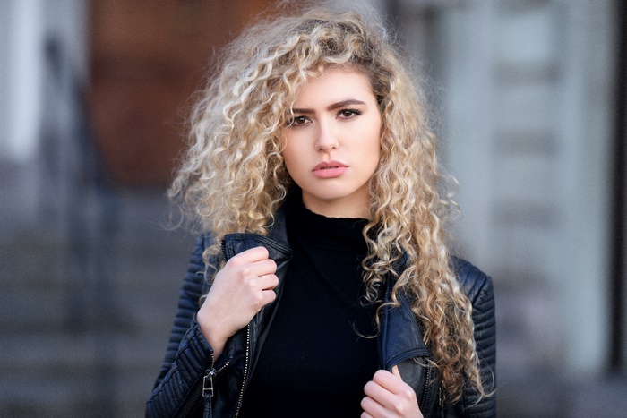 Woman with blonde curly hair wearing a leather jacket