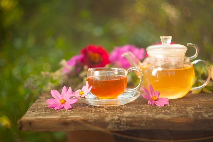 Tea in a glass cup and teapot with flowers