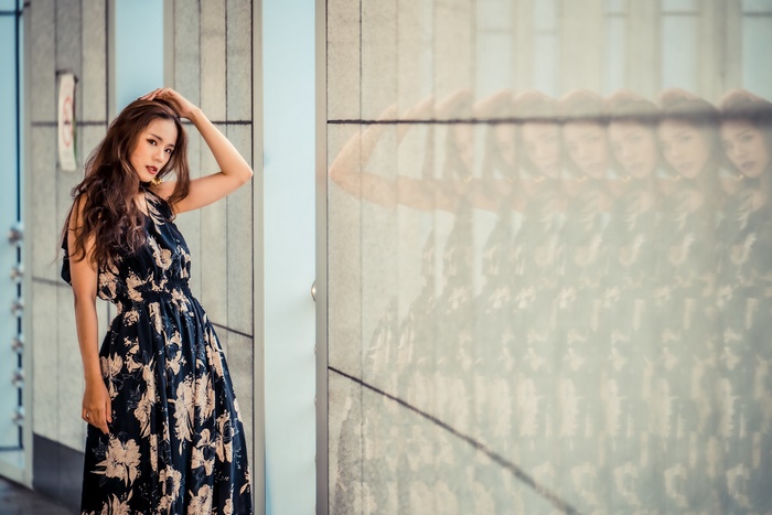 Woman in a floral dress posing near a reflective wall