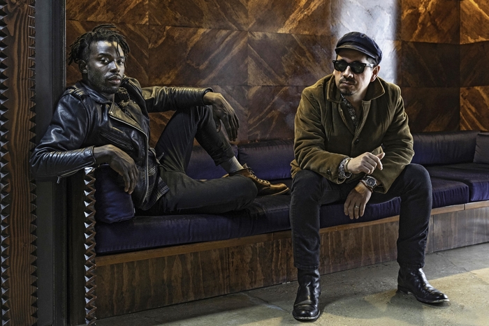 Black Pumas duo sitting on a couch