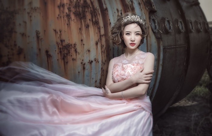 Woman in pink dress with tiara by rusty metal