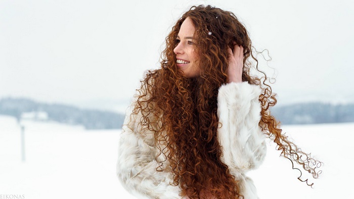 Woman with long curly red hair in a snowy landscape
