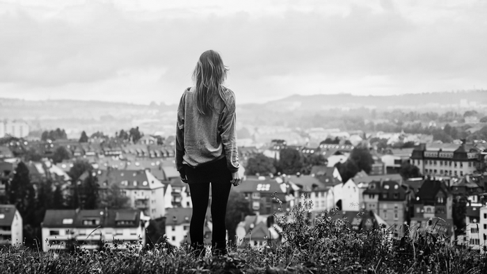 Woman looking over a city from a hill