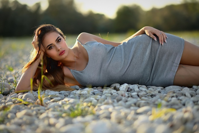 Brunette Woman in Gray Dress on Pebbles