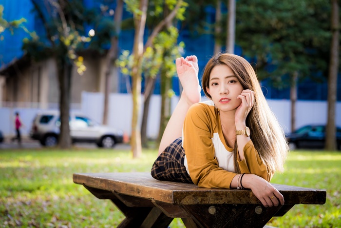 Asian woman lying on a park bench