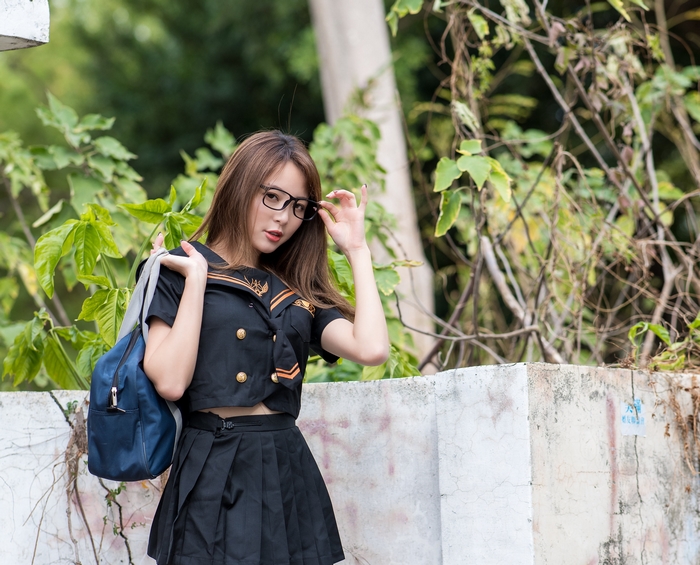 Asian woman in school uniform with glasses and backpack