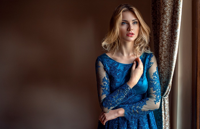 Woman in a blue dress by the window