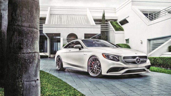 White Mercedes-Benz S63 AMG Coupe in front of modern house