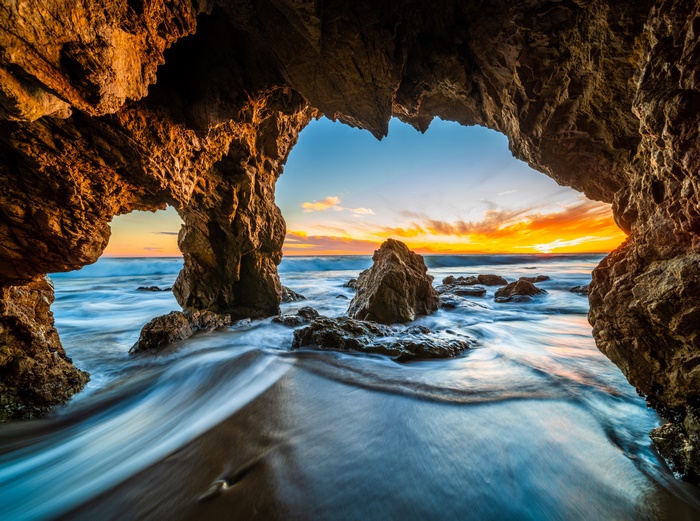 Cave entrance overlooking ocean at sunset