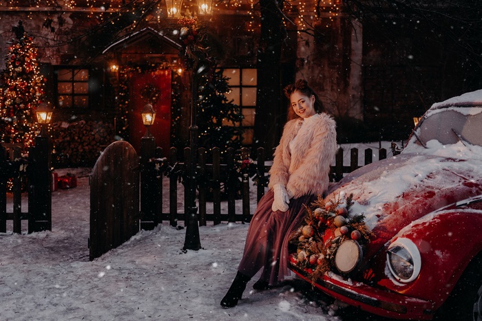 Woman in fluffy coat by red car in winter