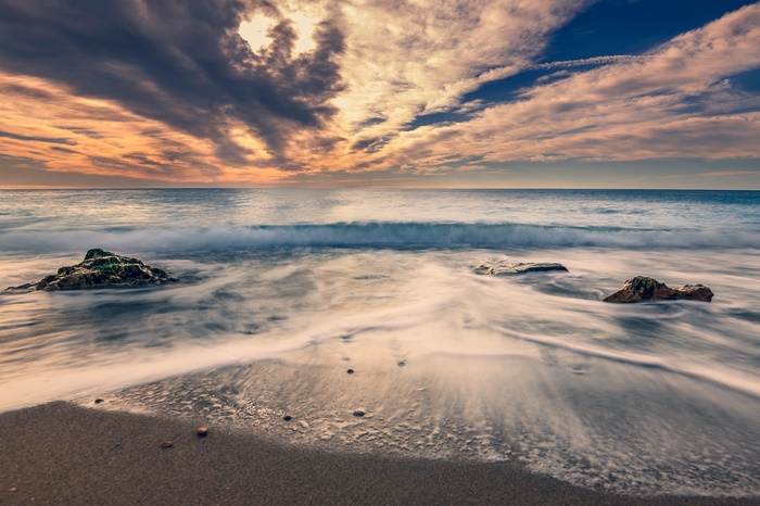 Ocean waves crashing on a beach at sunset