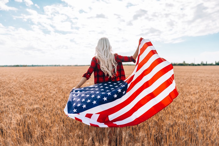 Woman with American Flag in Wheat Field
