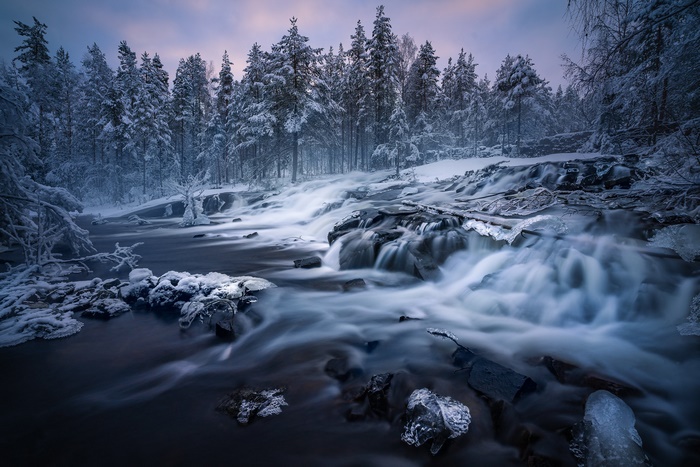 Winter waterfall in a snowy forest in Norway
